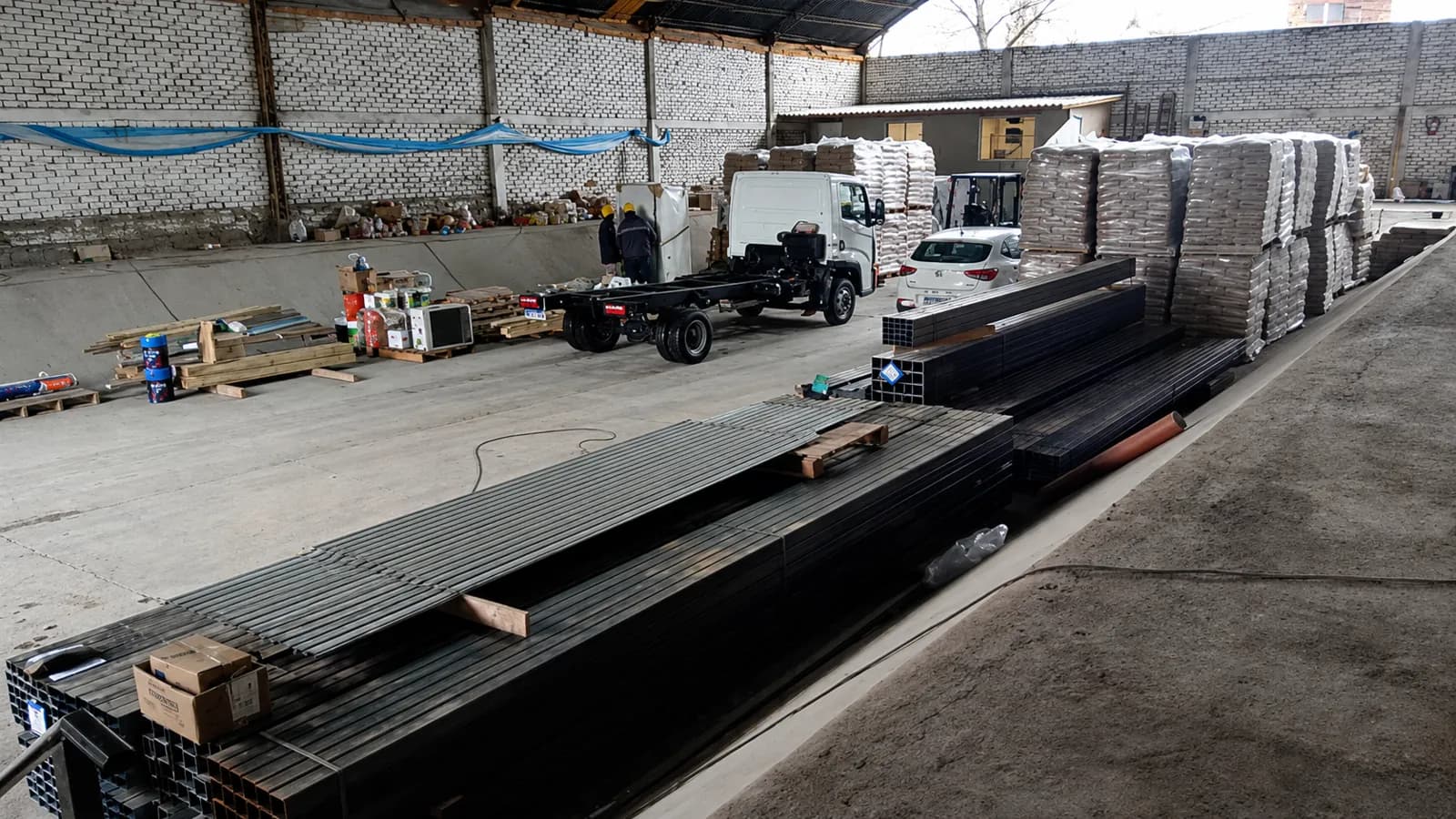 Obrador con materiales, perfiles y vehículos de obra